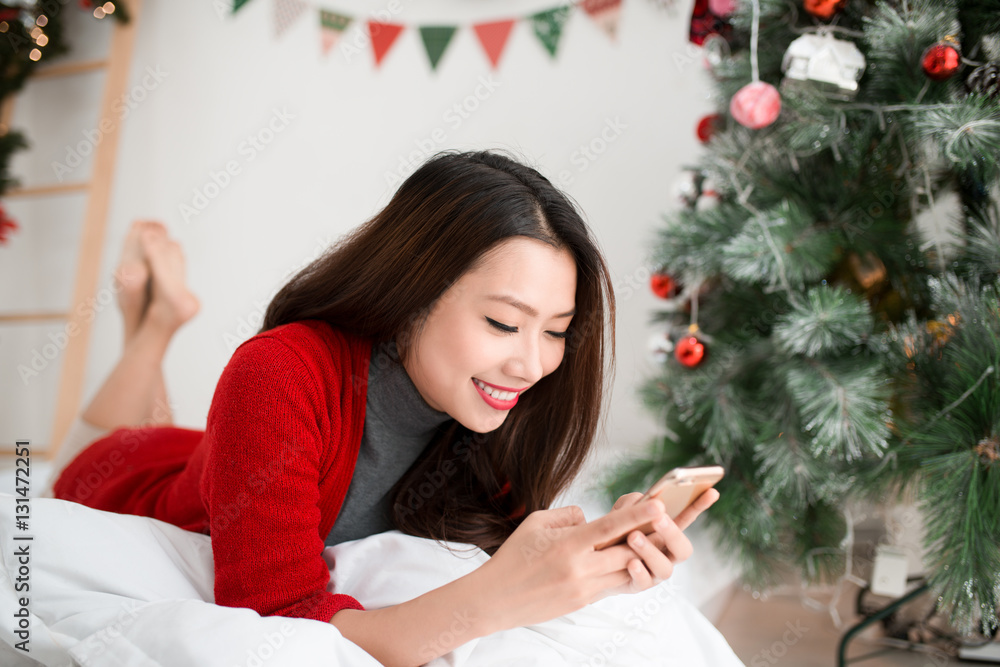 Young smiling asian woman is using mobile phone. Christmas and N Young smiling asian woman is using mobile phone. Christmas and N