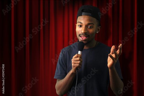 Fotografie young singer vocalist on stage live show red curtain