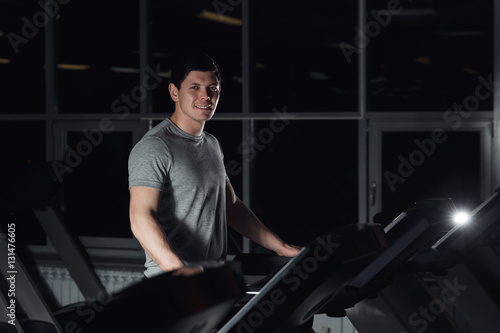 man smiling at the gym doing exercise on the treadmill.