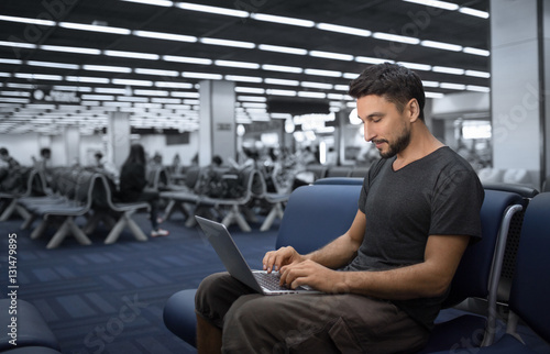 Man use notebook or laptop computer  in the airport © Glebstock