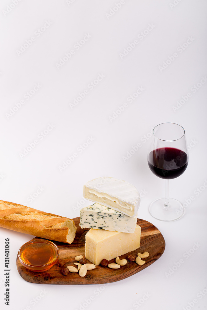 Fototapeta Still-life cheese platter with nuts, honey and wine on white background