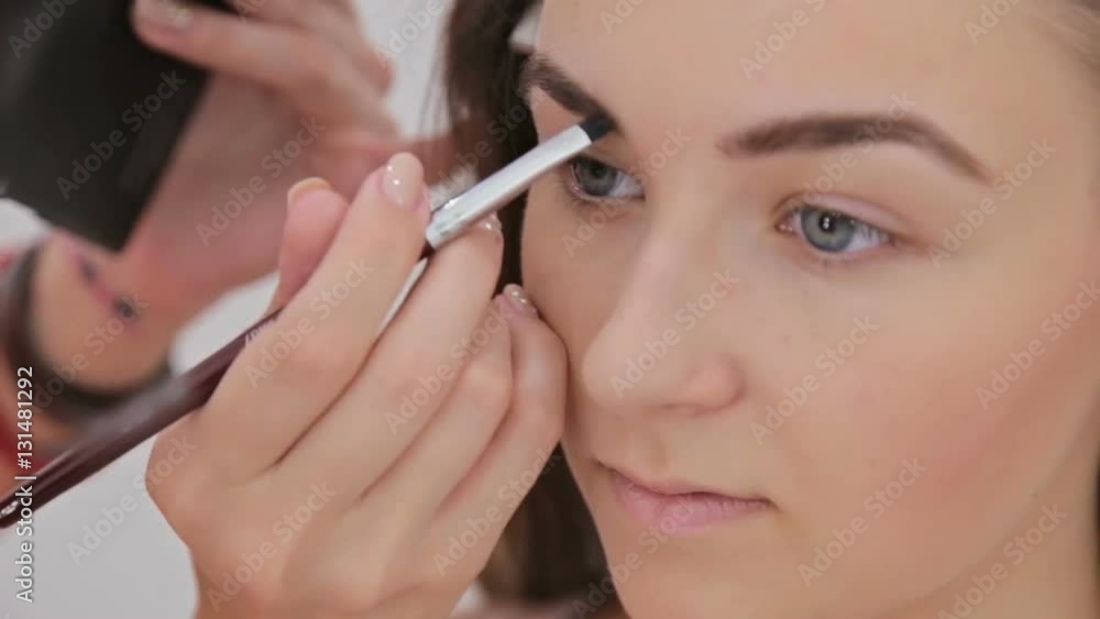 Close up shot. Professional make-up artist drawing eyebrows of client in white room. Beauty, makeup and fashion concept Close up shot. Professional make-up artist drawing eyebrows of client in white room. Beauty, makeup and fashion concept