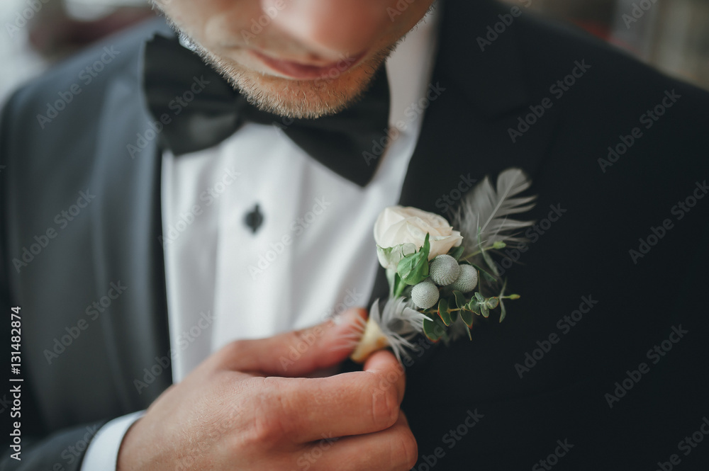young groom boutonniere in his hand closeup - obrazy, fototapety, plakaty 