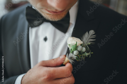 young groom boutonniere in his hand closeup photo