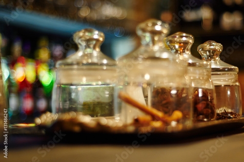 Glass with aromatic spices. Bar in the background, out of focus.