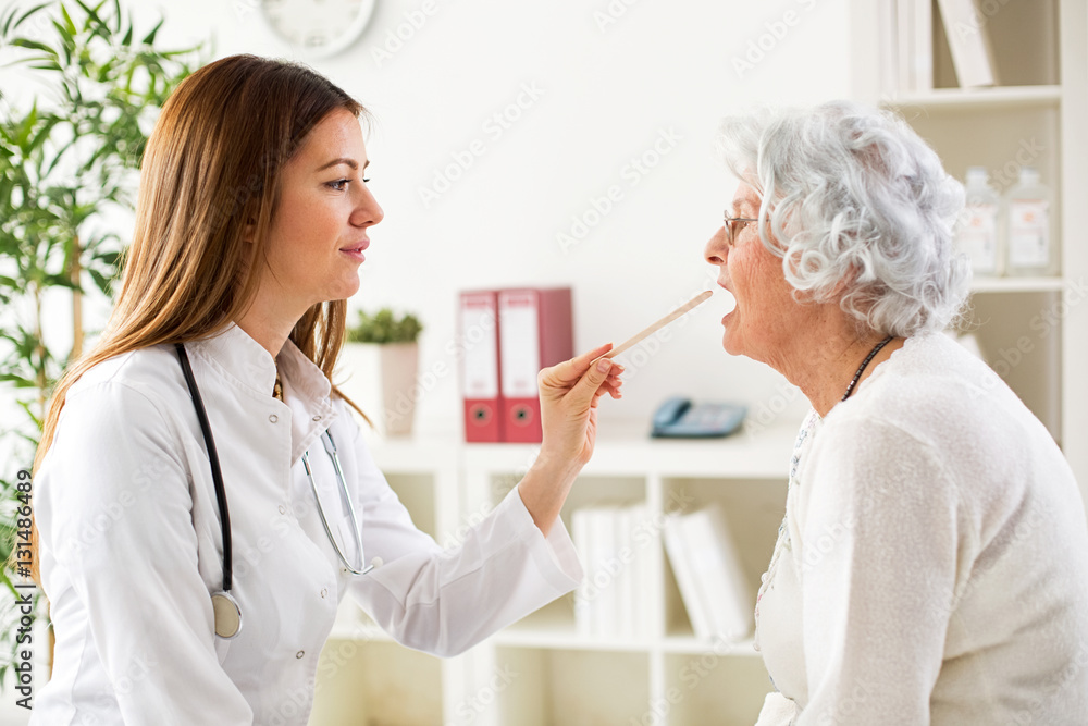 Beautiful young doctor examining throat to senior woman Beautiful young doctor examining throat to senior woman
