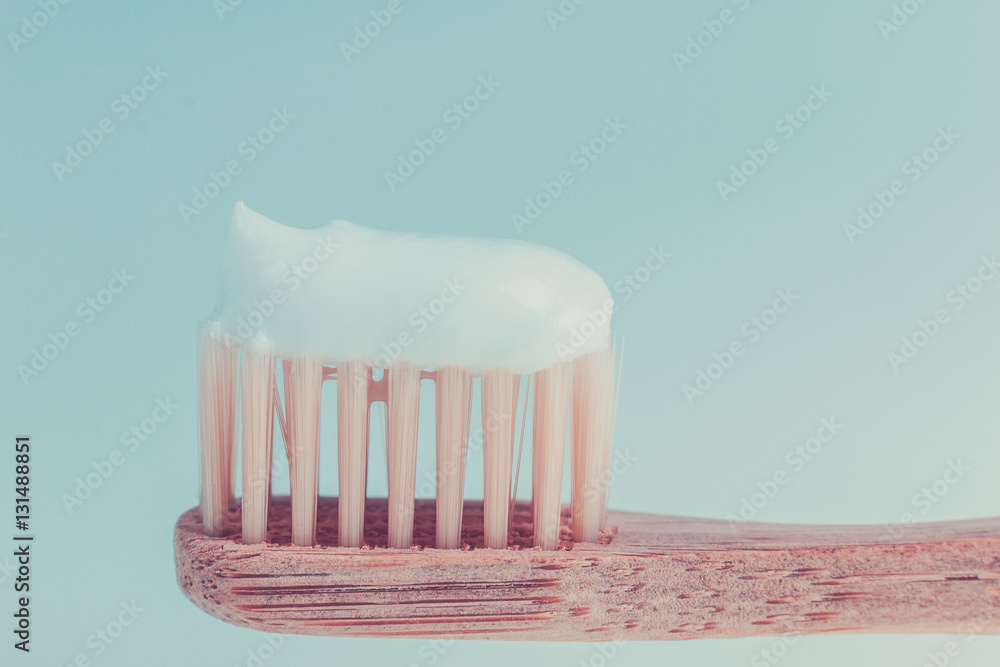 Beige dental brush with white toothpaste on blue background. Isolated. Close up. Beige dental brush with white toothpaste on blue background. Isolated. Close up.