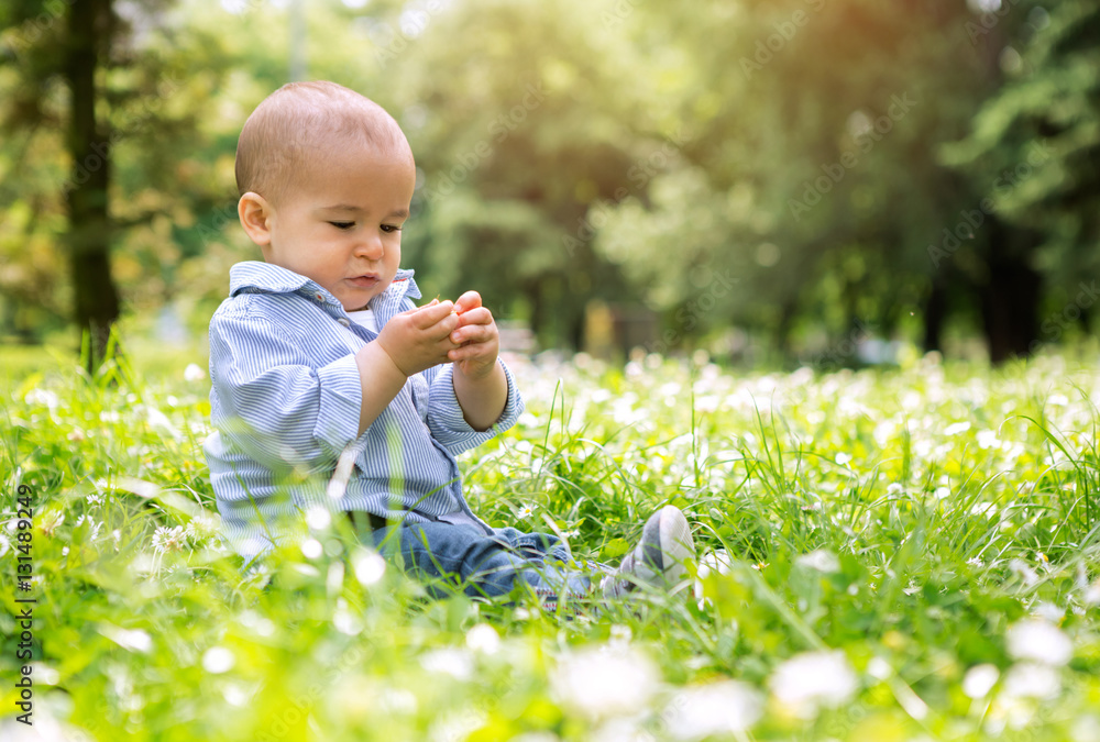 Happy small baby boy sitting on green grass in a park Happy small baby boy sitting on green grass in a park