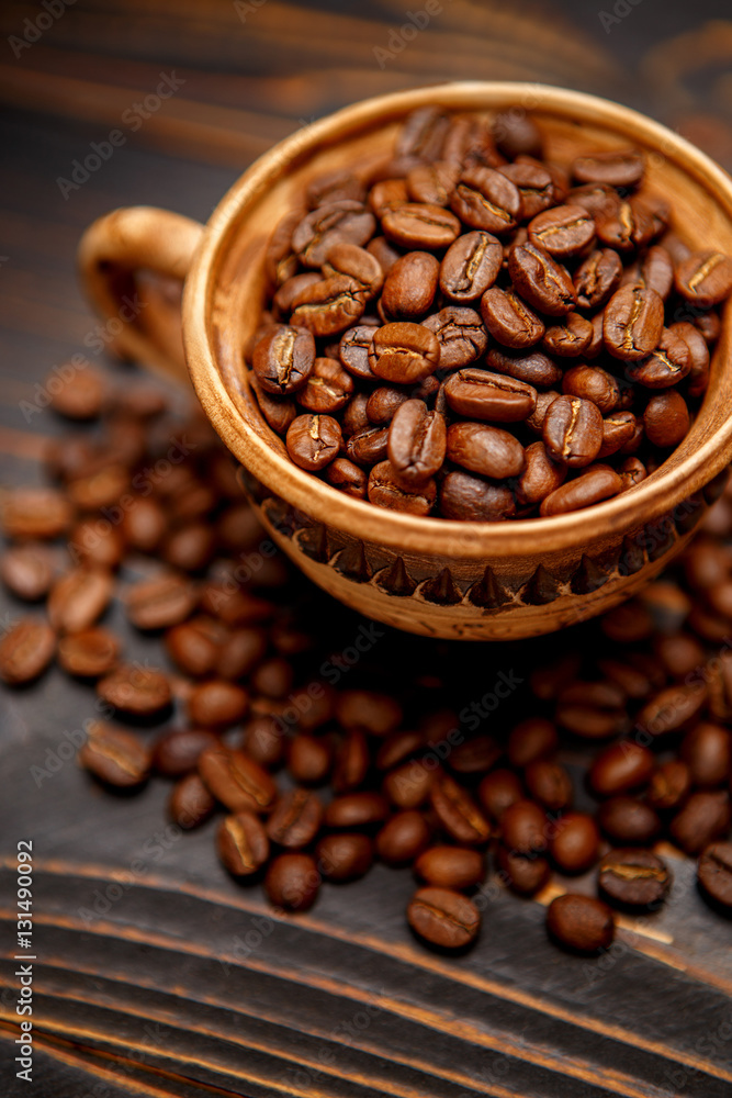 Fototapeta premium mug with roasted coffee beans on wooden background