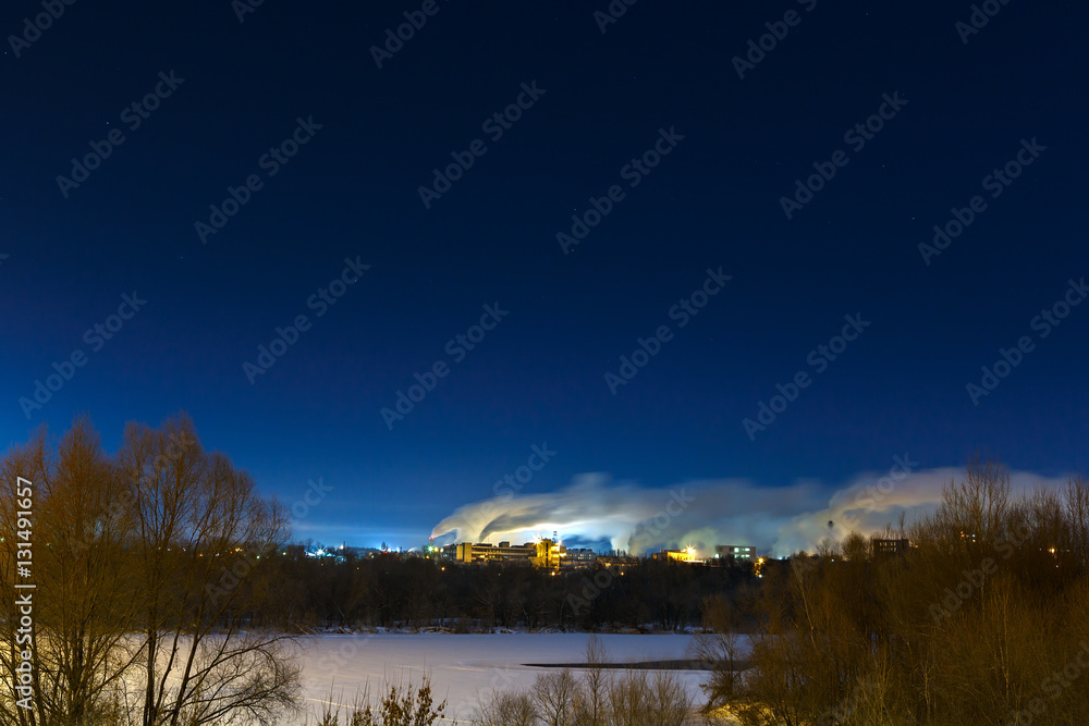 Industrial area on the banks of the river. Night winter landscap