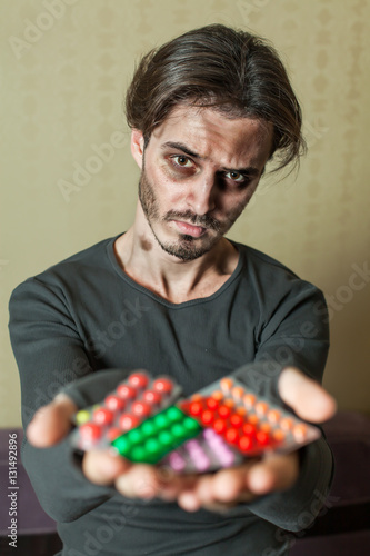 Fotografie Drugs addict is holding tablets in both his hands