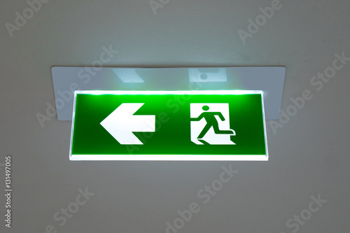 green emergency exit sign showing the way to escape. photo