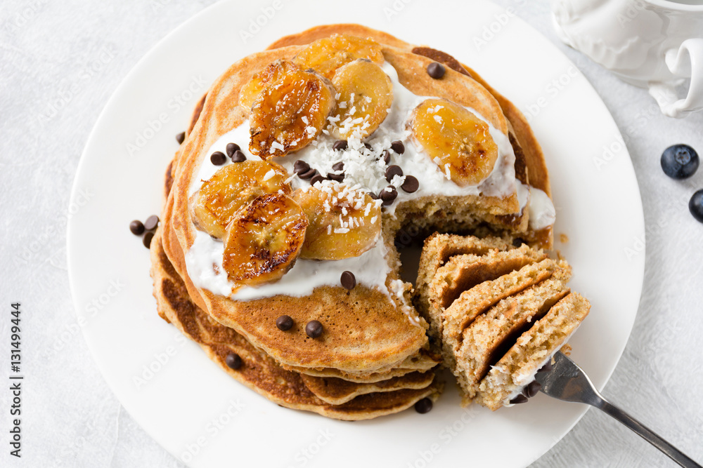 Healthy pancakes, whole grain pancakes with banana, yogurt and chocolate chips on white plate. Close up view Healthy pancakes, whole grain pancakes with banana, yogurt and chocolate chips on white plate. Close up view