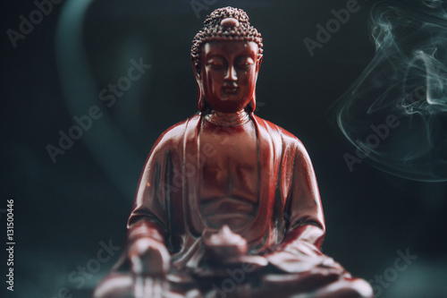 Buddha statue with incense. Deity and symbols of Buddhism. The practice of Buddhism and its symbols. Spiritual life of Asia
