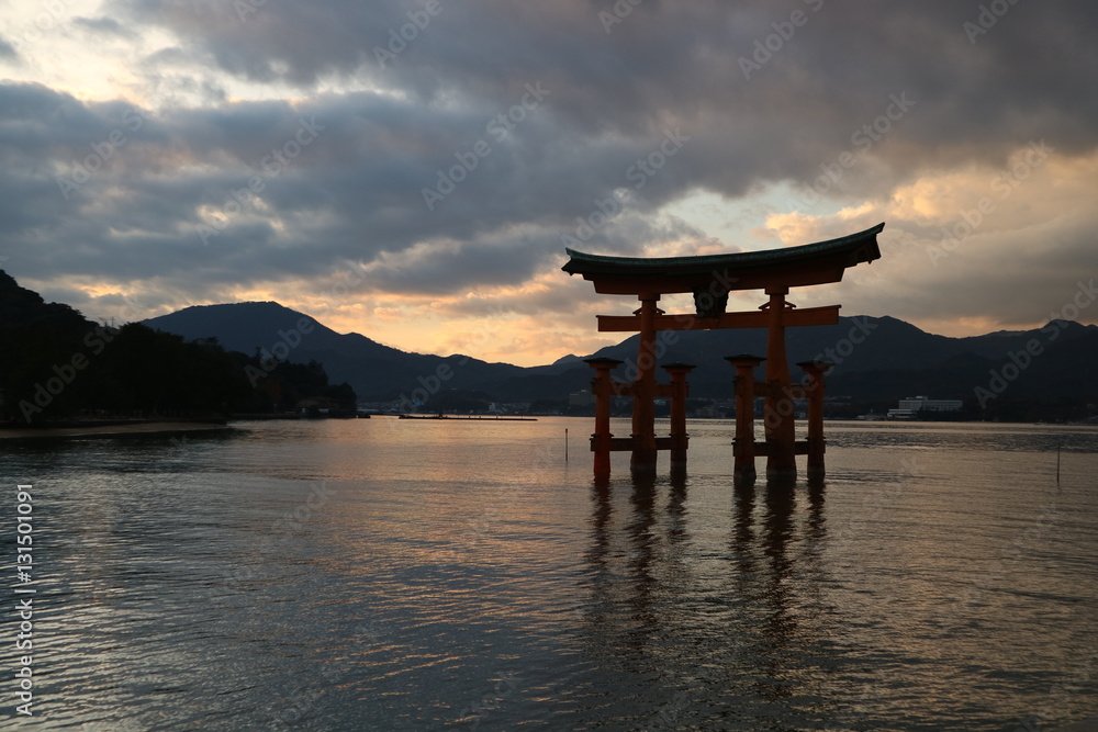 The Otori of Itsukushima shrine that backed the sunset covered with white clouds reflects the sea surface like a mirror, creating a majestic atmosphere The Otori of Itsukushima shrine that backed the sunset covered with white clouds reflects the sea surface like a mirror, creating a majestic atmosphere