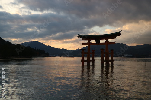 The Otori of Itsukushima shrine that backed the sunset covered with white clouds reflects the sea surface like a mirror, creating a majestic atmosphere