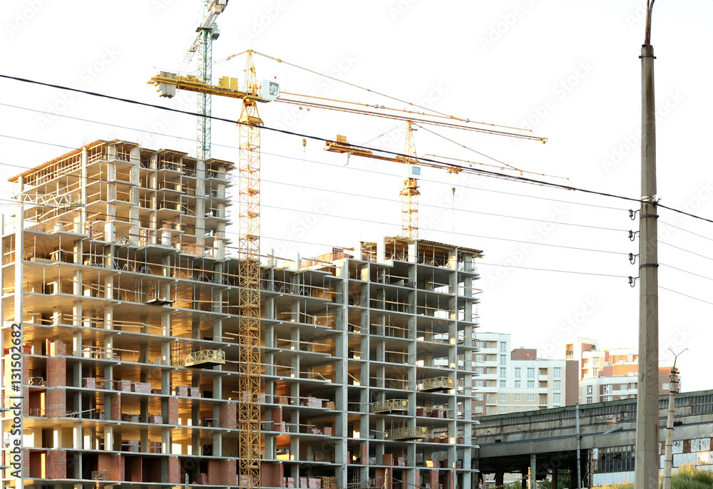 Construction cranes and building on blue sky background