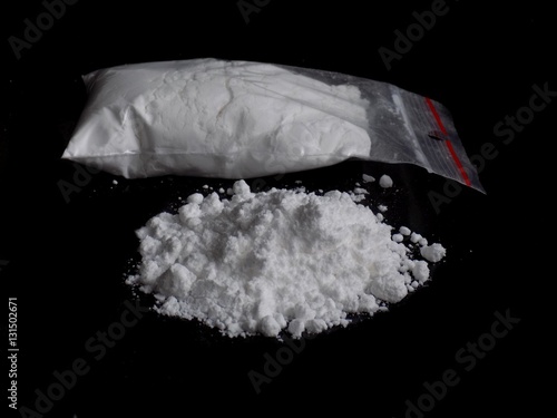 Cocaine drug powder pile and bag on black background