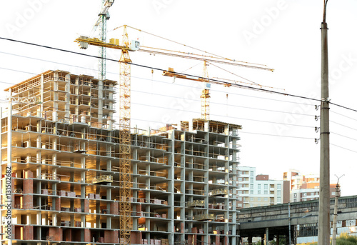 Construction cranes and building on blue sky background © Africa Studio