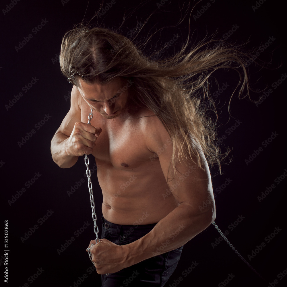 Young man with long hair dragging something behind him. Strong. Stock Photo  | Adobe Stock