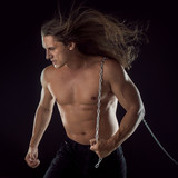 Young man with long hair dragging something behind him. Strong.