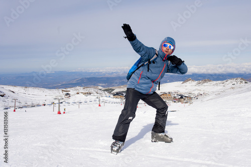 man doing victory sign after peak summit trekking achievement in snow mountain on winter landscape