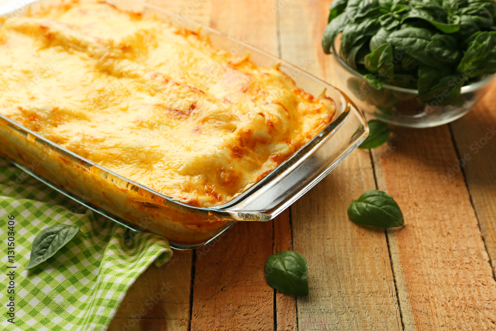 Traditional lasagna in glass baking dish and napkin on wooden table Traditional lasagna in glass baking dish and napkin on wooden table