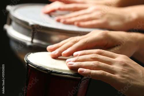 Hands of man playing African drum on dark background  close up