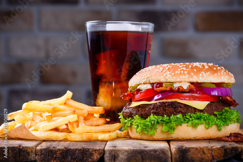 Fresh hamburger with french fries and cola on wooden table