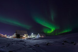 Row of cabins and green Northern lights in a suburb of Nuuk