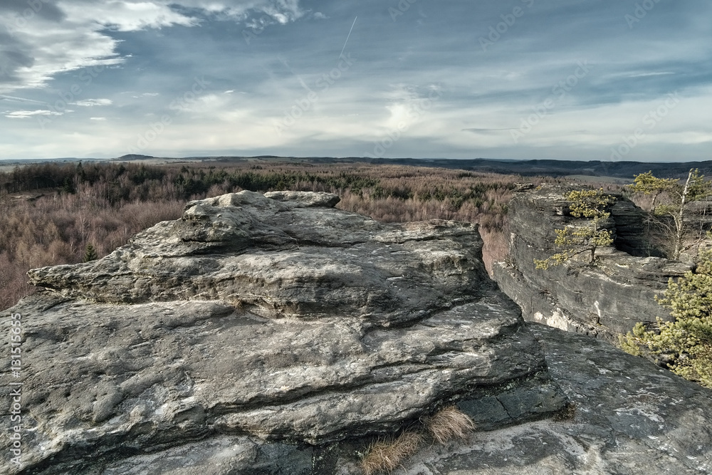 view from rocks to forest of czech Krusne hory mountains in winter without snow
