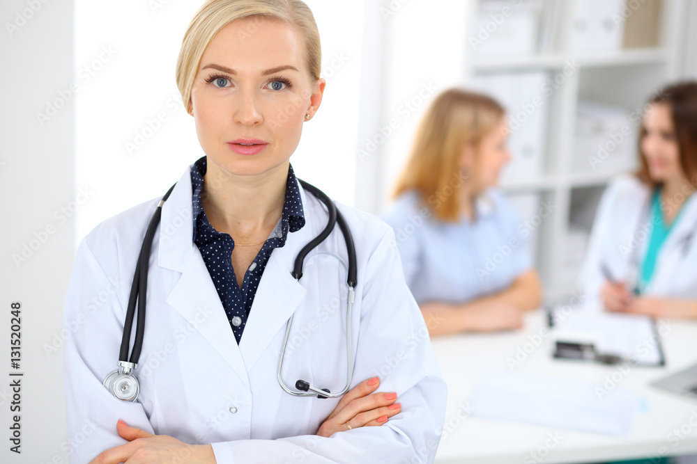 Female doctor smiling on the background with patient and his physician in hospital Female doctor smiling on the background with patient and his physician in hospital