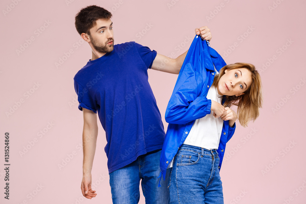 Obraz premium Young beautiful couple posing having fun over light pink background.