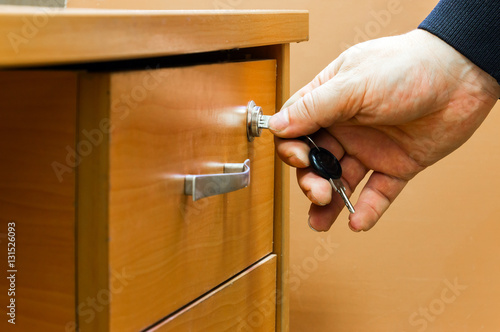 Obraz na plátně The man closes the drawer of the desk
