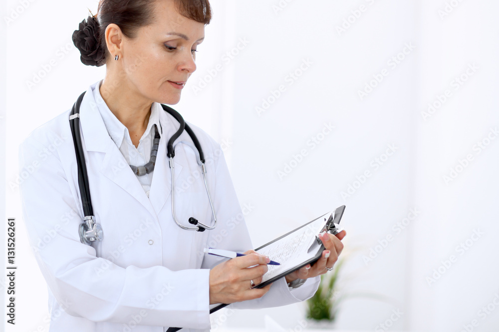 Happy female doctor standing in hospital. Medicine and health care concept. Happy female doctor standing in hospital. Medicine and health care concept.