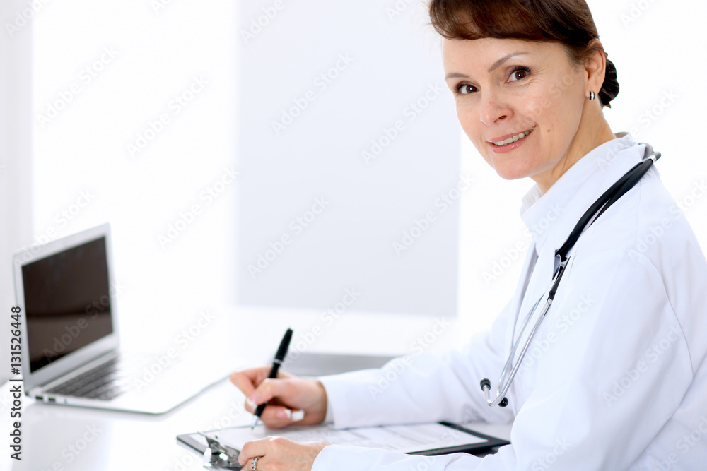 Female doctor at the table and filling up medical form. Medicine and health care concept. Female doctor at the table and filling up medical form. Medicine and health care concept.