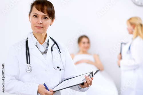 Female doctor smiling on the background with patient and his doctor