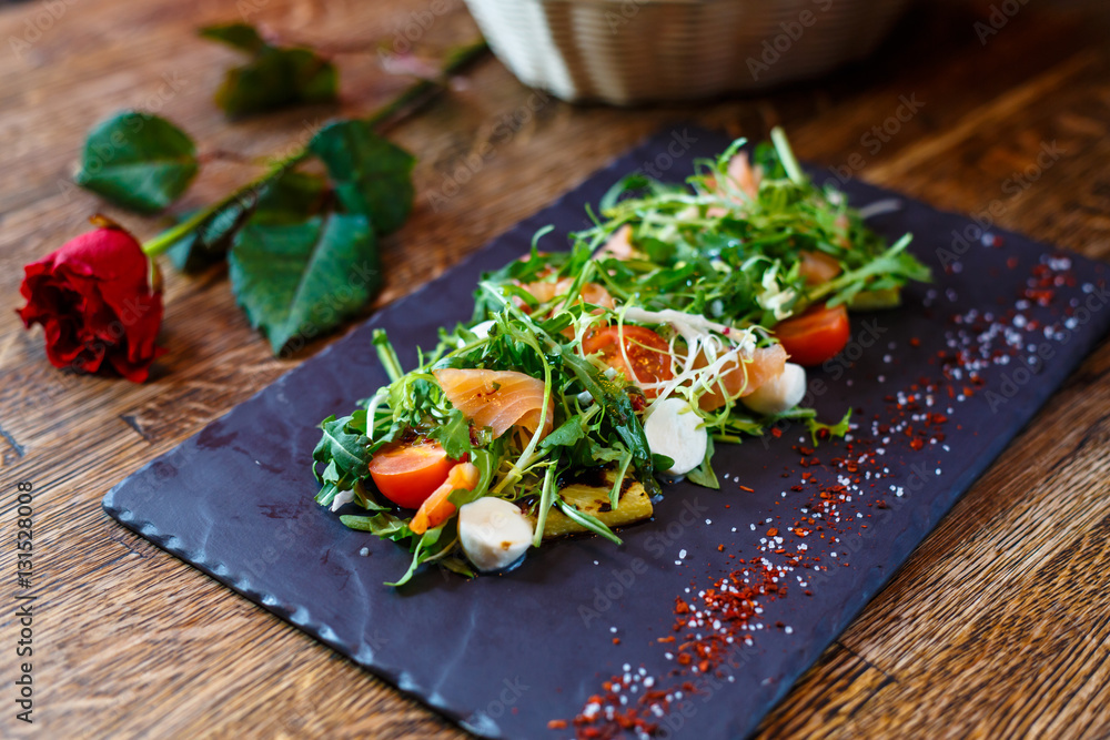 Salad with salted salmon with arugula and mozzarella on a black Salad with salted salmon with arugula and mozzarella on a black