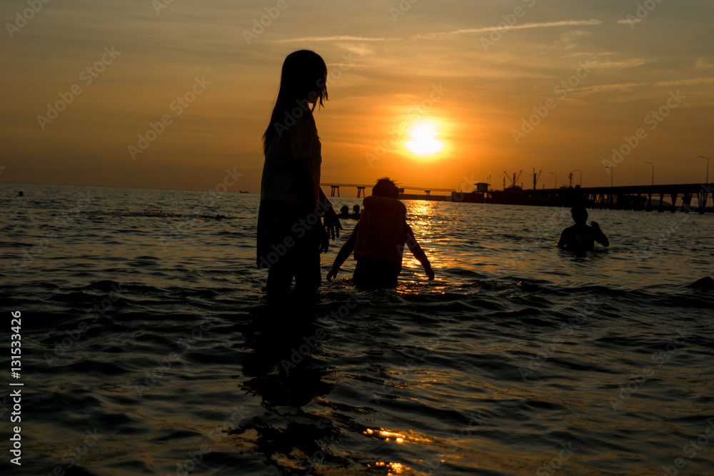People walk ocean beach sunset