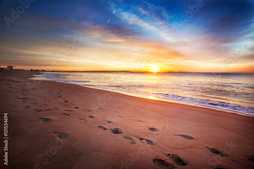 Fototapeta Naklejka Na Ścianę i Meble -  Footprints along a Maine beach as sun comes over the horizon