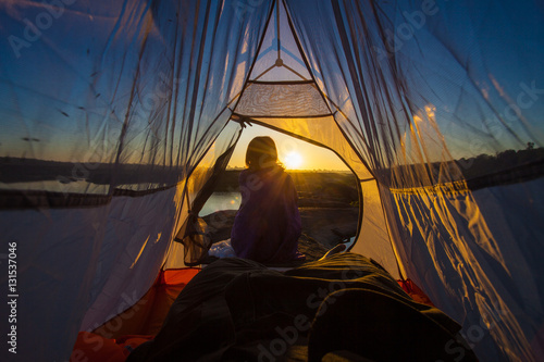women sit front of tent with sunrise