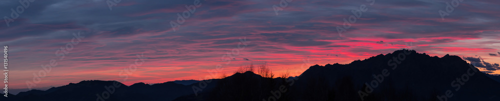 Fiery sunset from mountain pick in a cloudy evening. Fall season. Orobie mountains. Italian Alps.