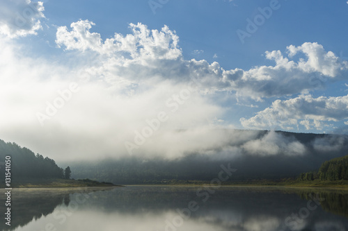 Summer landscape with river, forest, clouds on the blue sky and sunset. © Olonkho
