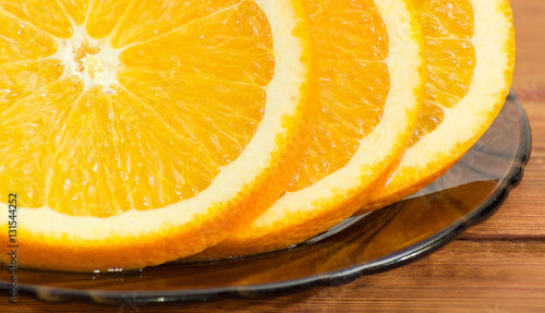 Fragment of orange slices on a glass saucer closeup
