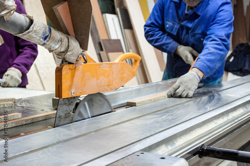 Worker using saw machine to make furniture at carpenters worksho photo