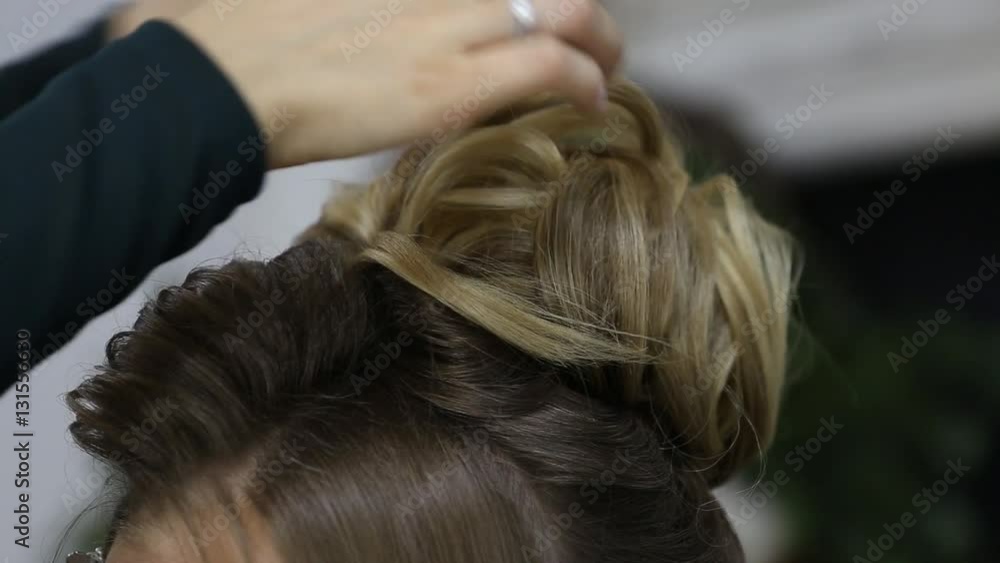 Hairdresser creating complicated evening and wedding hairstyles at barbershop salon. Close-up of hands corrects hair curls and strands Hairdresser creating complicated evening and wedding hairstyles at barbershop salon. Close-up of hands corrects hair curls and strands