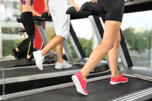Young people running on treadmills in gym, close up view