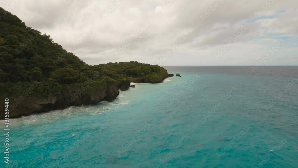 Rocky shore on the tropical sea with the rainy cloud. Aerial view:Stormy weather on island.Rocks in sea in cloudy gloomy weather. Big waves crushing on the shore of a tropical island with palm trees Rocky shore on the tropical sea with the rainy cloud. Aerial view:Stormy weather on island.Rocks in sea in cloudy gloomy weather. Big waves crushing on the shore of a tropical island with palm trees