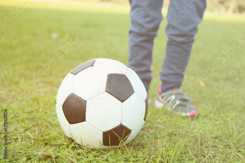 Close up view of boy's legs and ball on green grass © Africa Studio