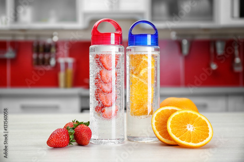 Bottles with fruit-infused water on kitchen table photo